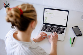 Foto einer Frau, die auf einen Laptop blickt.