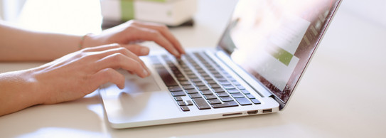 Studentin tippend am Laptop, daneben liegen Bücher.